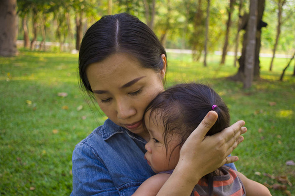 junge Mutter umarmt und besänftigt eine weinende kleine Tochter, Asien - Foto, Bild