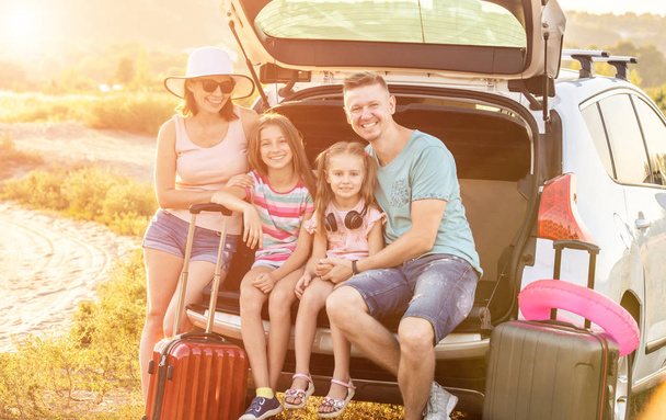 Happy family sitting on a trunk of a car with on a travel vacation - Φωτογραφία, εικόνα