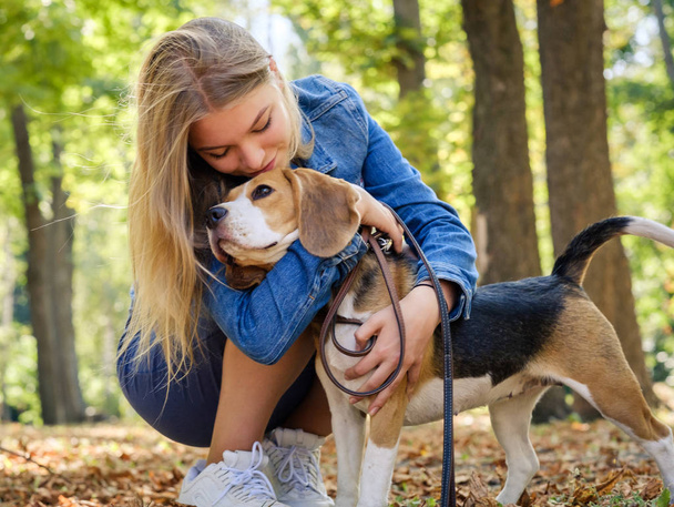 Pretty blond girl sit hugging beagle dog - Fotografie, Obrázek