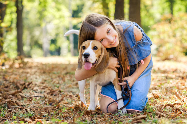 Little smiling blond girls sit hugging beagle dog - Photo, Image