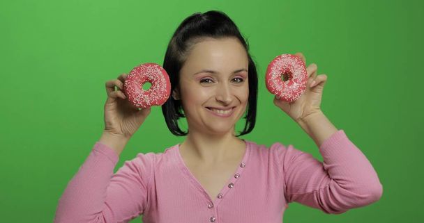 Onnellinen kaunis nuori tyttö poseeraa ja pitää hauskaa donitseja. Kroma-avain
 - Valokuva, kuva