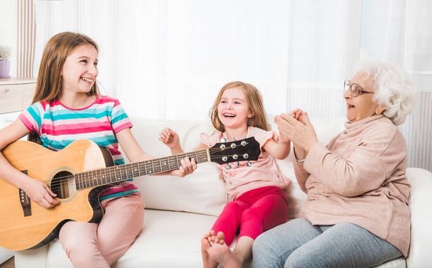 Granddaughters with grandmother listening the guitar - Фото, зображення