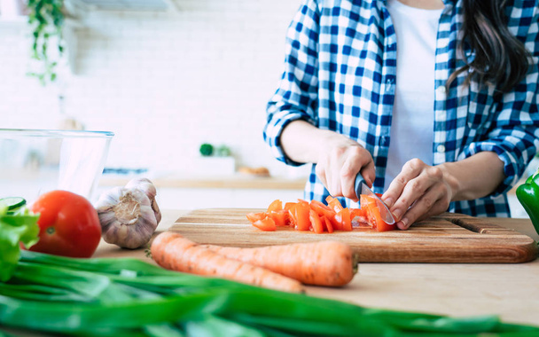 Vrouwelijke handen is snijden pepers voor salade op de tafel in de keuken. - Foto, afbeelding