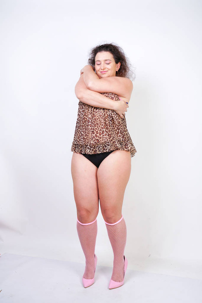 Plump woman in leopard print lingerie nightgown and pink mesh socks posing on white studio background alone isolated - Фото, зображення