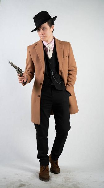 Young man in a formal suit and hat with a gun in his hands on a white background in the Studio alone isolated - Photo, Image