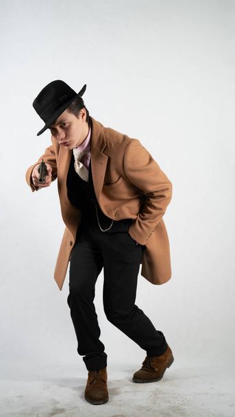 Young man in a formal suit and hat with a gun in his hands on a white background in the Studio alone isolated - Fotoğraf, Görsel