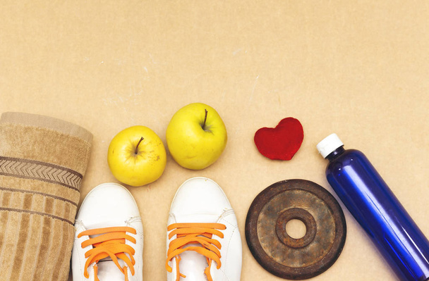 Sports equipment flat lay, and sneakers, old metal dumbbells and apples, water bottle and heart pillow. Concept healthy lifestyle, sport and diet. - Photo, Image