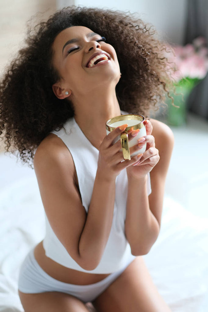 Beautiful afroamerican girl in the bed drinking coffee. - Photo, Image