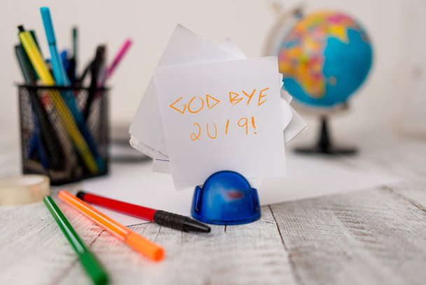 Text sign showing God Bye 2019. Conceptual photo express good wishes when parting or at the end of last year Stationary plus pens and papers with artificial globe on the wooden desk. - Photo, Image