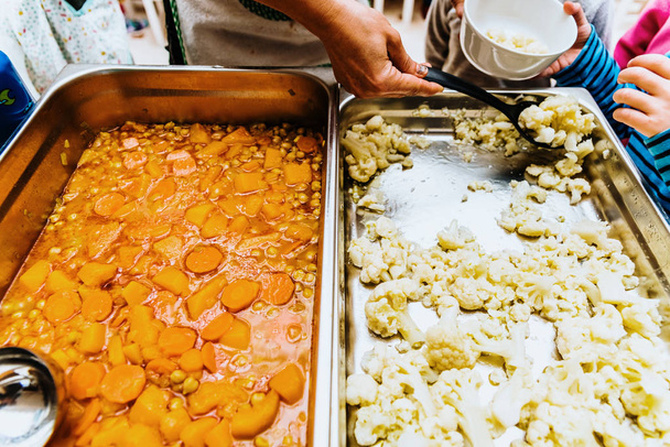 Cucinare servendo i bambini in una mensa scolastica verdure arrosto e
 - Foto, immagini