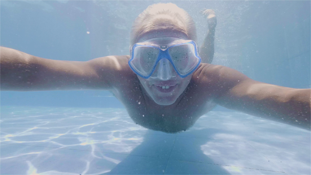 Homem sorridente mostrando os polegares para cima enquanto nadava sob a água na piscina do hotel resort. Enfrente o homem feliz nadando na piscina flutuante de água azul. Pessoas positivas emoções
. - Filmagem, Vídeo
