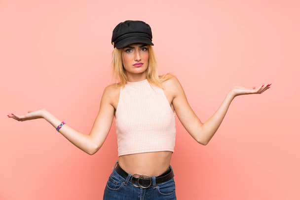 Young blonde woman with hat unhappy for not understand something - 写真・画像