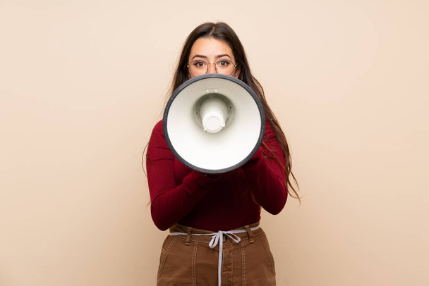 Teenager girl with glasses shouting through a megaphone - Foto, afbeelding