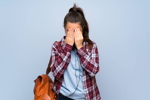 Студентська дівчина-підліток над ізольованою синьою стіною з втомленим і хворим виразом
 - Фото, зображення