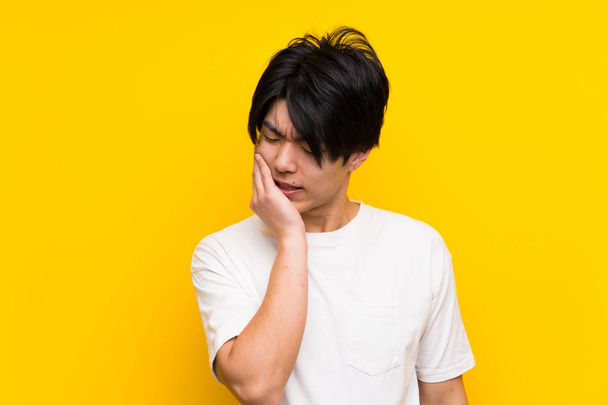 asiático hombre sobre aislado amarillo pared con dolor de muelas
 - Foto, Imagen