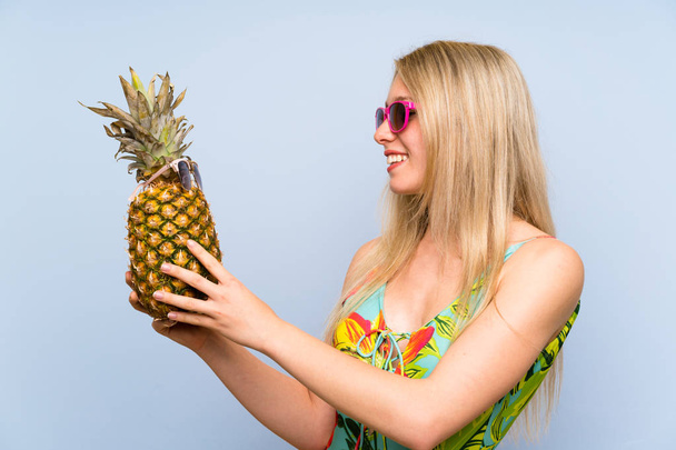 Молода жінка в купальнику тримає ананас із сонцезахисними окулярами
 - Фото, зображення