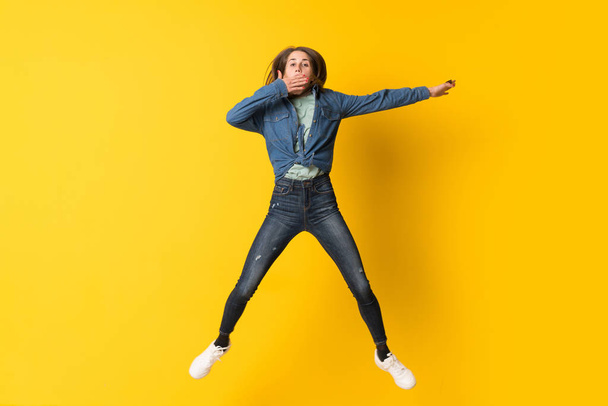 Young woman jumping over yellow background - 写真・画像