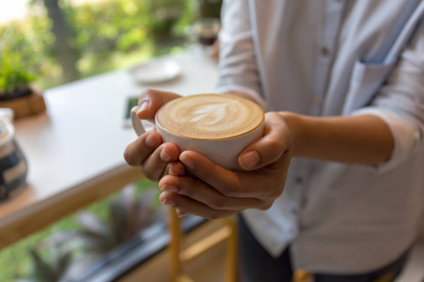 Жінка рука тримає чашку кави в кав'ярні
 - Фото, зображення