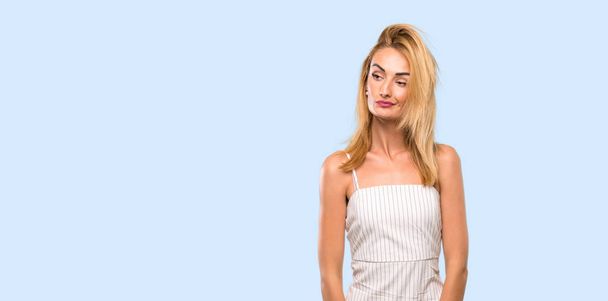 Young blonde woman making doubts gesture looking side over isolated blue background - Foto, Imagen