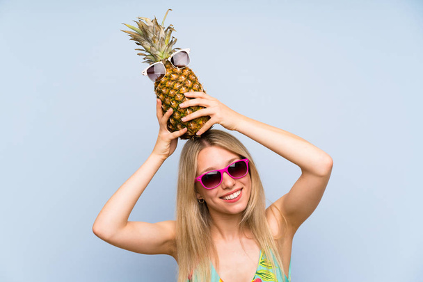 Νέα γυναίκα με μαγιό κρατώντας έναν ανανά με γυαλιά ηλίου - Φωτογραφία, εικόνα