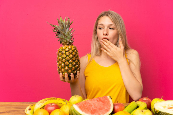 Jonge vrouw met veel fruit vasthouden van een ananas - Foto, afbeelding