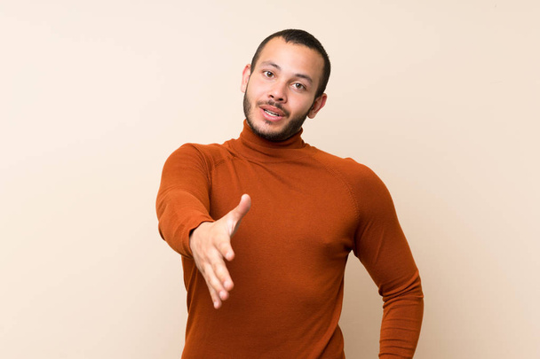 Hombre colombiano con jersey de cuello alto estrechando las manos para cerrar una buena oferta
 - Foto, Imagen