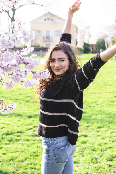 Girl stands near blossom tree and enjoys life - Fotoğraf, Görsel