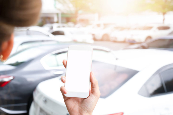 Otoparkta beyaz ekranlı el ele tutuşan akıllı telefon - Fotoğraf, Görsel