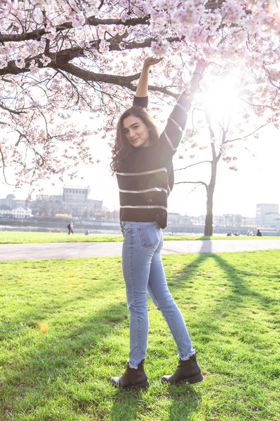 Girl stands near blossom tree and pulls up hands - Φωτογραφία, εικόνα