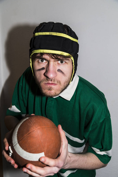 Rugby sportsman with ball in hand looks at camera - Foto, Imagem