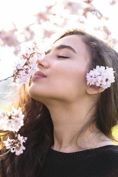 Girl with pleasure smells branch with flowers - Foto, imagen