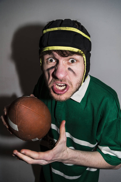 Rugby player holding ball in hand and making faces - Foto, Imagen
