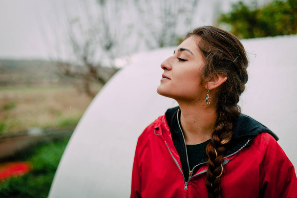 Chica en impermeable rojo huele el aire en el campo
 - Foto, Imagen