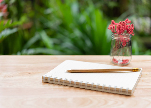 Cuaderno, lápiz marrón y hermosa flor roja seca en vidrio va
 - Foto, imagen