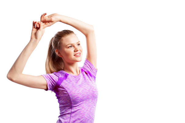 Una joven atleta delgada con un top deportivo rosa levantó las manos y hizo un ejercicio para bíceps, estirándose sobre un fondo blanco aislado en el estudio. Retrato de una hermosa mujer deportista
 - Foto, Imagen