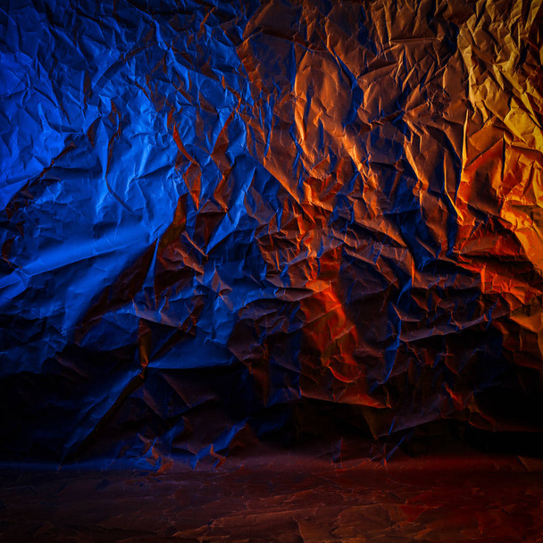 Tekstuuri rypistynyt musta paperi. Lähikuva musta tausta rypistynyt pahvi väri sininen ja oranssi studio valo
 - Valokuva, kuva