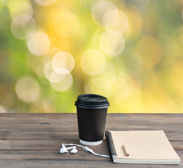 Black coffee cup,white earphone,memo notebook and pencil on wood - Zdjęcie, obraz