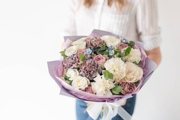 Beautiful bouquet of mixed flowers in woman hand. the work of the florist at a flower shop. Delicate Pastel color. Fresh cut flower. White and lilac color - Foto, Imagen