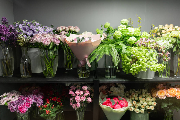 Flower shop concept. Glass vases with different flowers on the shelves of the refrigerator showcases. Abstract background of floral. Flowers composition. - Φωτογραφία, εικόνα