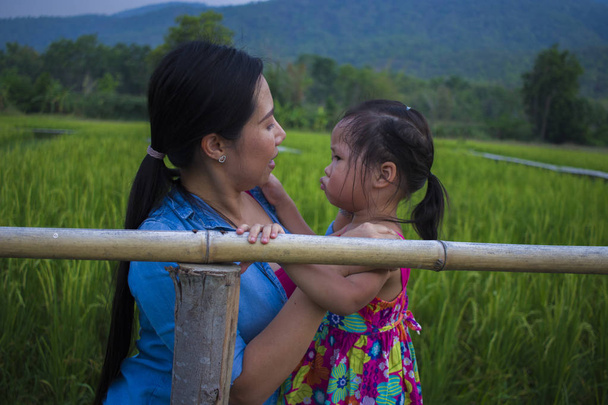 jonge moeder knuffelen en kalmeren een huilende kleine dochter, Azië - Foto, afbeelding