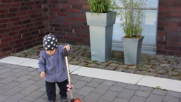 kleines Mädchen versucht, einen großen Roller zu fahren - Filmmaterial, Video