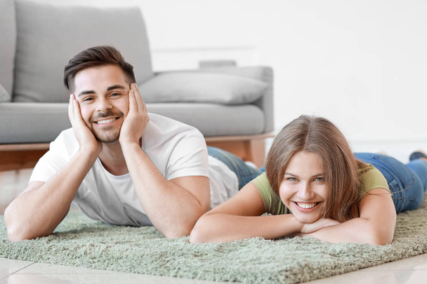 Jeune couple reposant sur un tapis mou à la maison
 - Photo, image