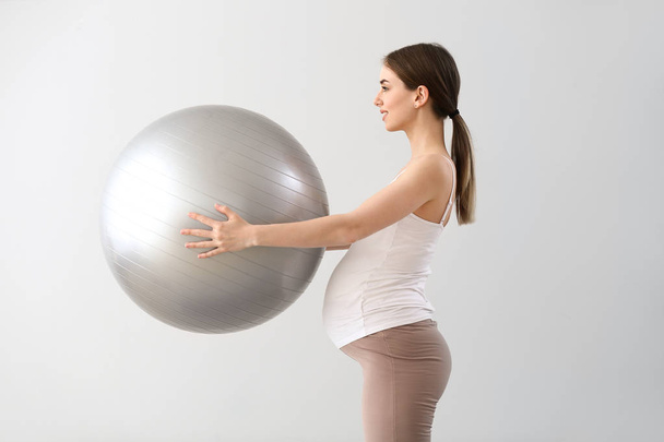 Kaunis raskaana oleva nainen, jolla on fitball-koulutus harmaalla taustalla
 - Valokuva, kuva