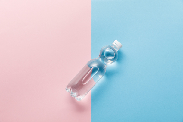 pohled na láhev s vodou na modrém a růžovém pozadí - Fotografie, Obrázek