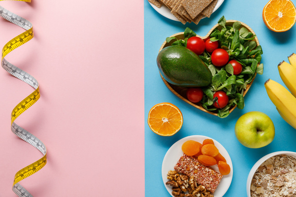 pembe arka planda mavi ve ölçme bandı üzerinde diyet gıda üst görünümü - Fotoğraf, Görsel