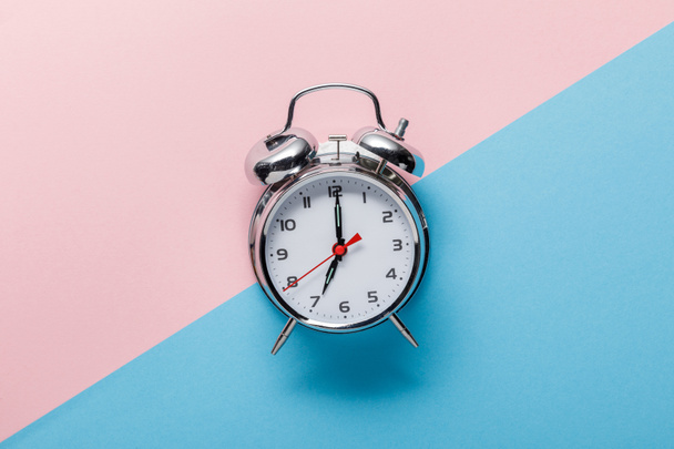 vista superior del reloj despertador clásico plateado sobre fondo rosa y azul
 - Foto, Imagen