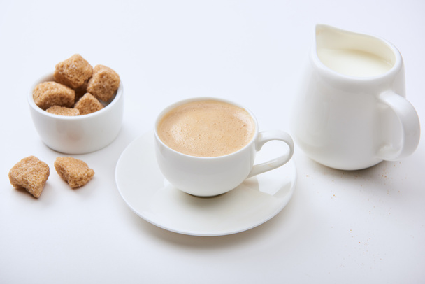 tasty coffee in cup near milk and brown sugar on white background - Foto, Bild