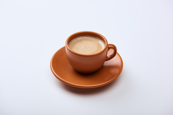 delicious coffee with foam in brown cup on saucer on white background  - Φωτογραφία, εικόνα