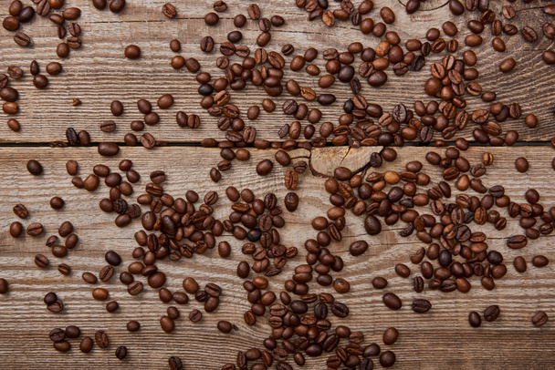 wooden weathered table with scattered roasted coffee beans - Photo, Image
