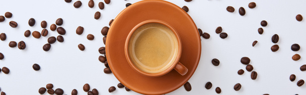 top view of delicious coffee in cup near scattered beans on white background, panoramic shot - Foto, Imagem